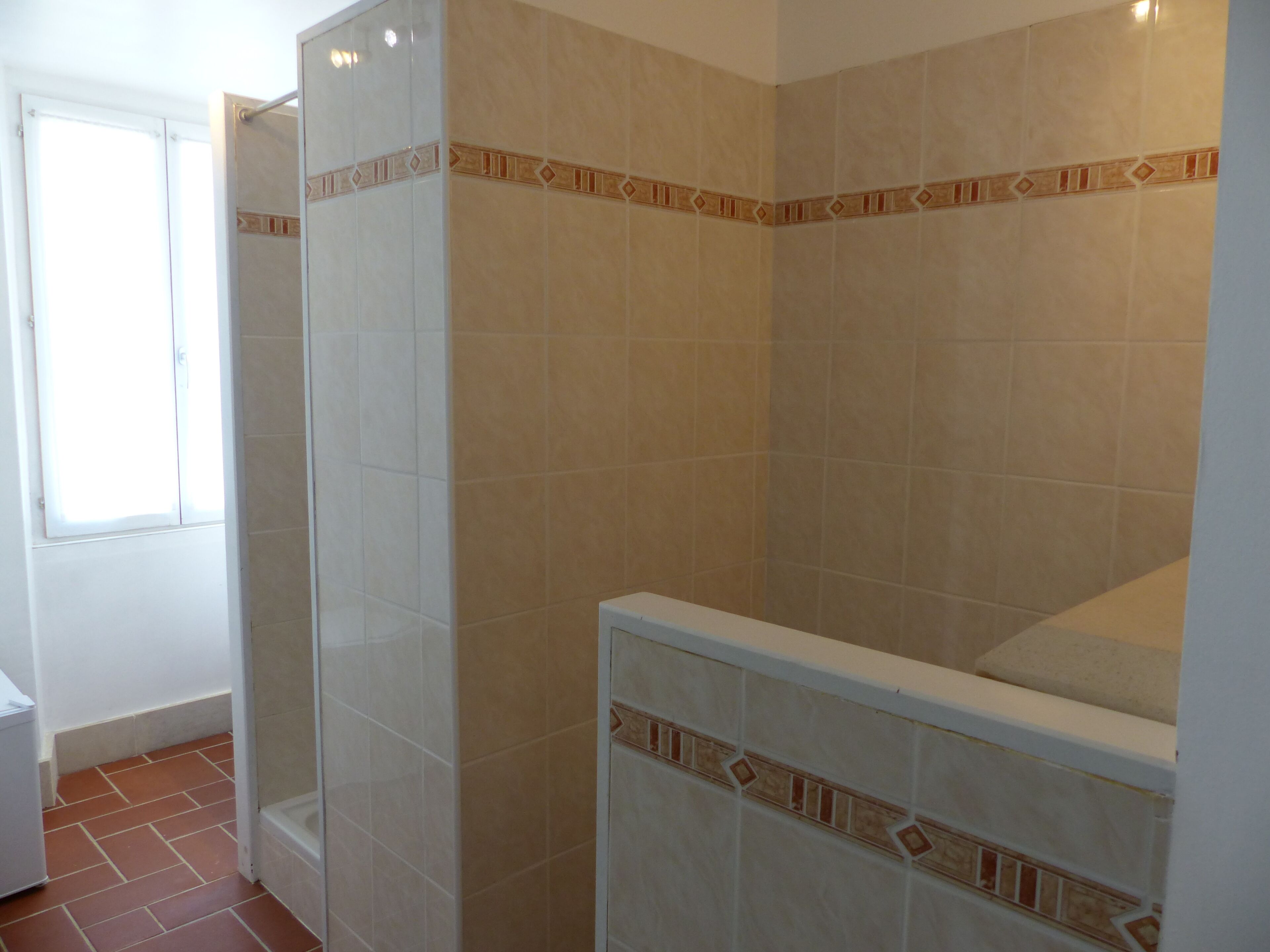 A bathroom with a shower, tiled walls, and a window.