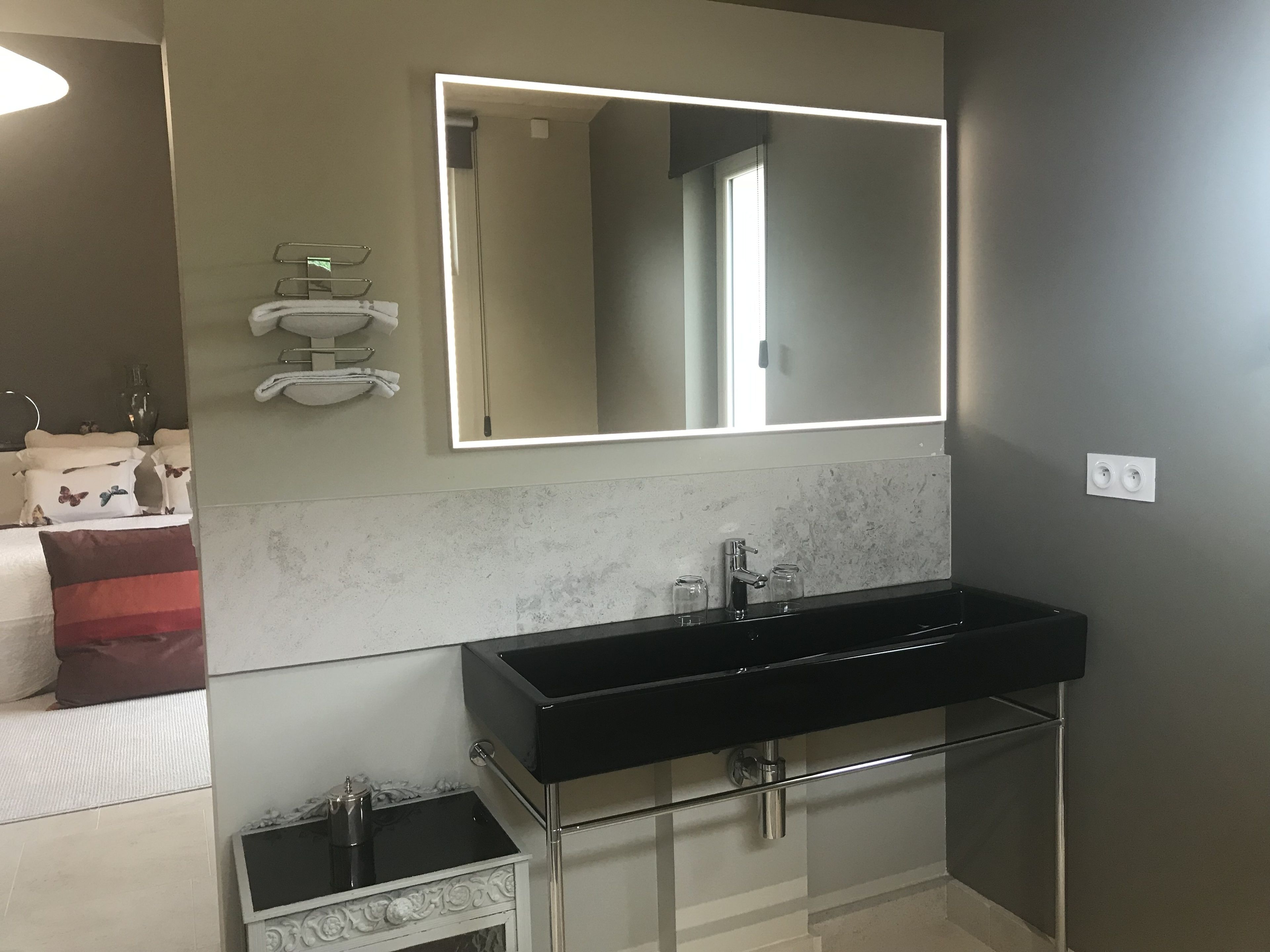A modern bathroom with a black sink, a large mirror, and a towel rack.