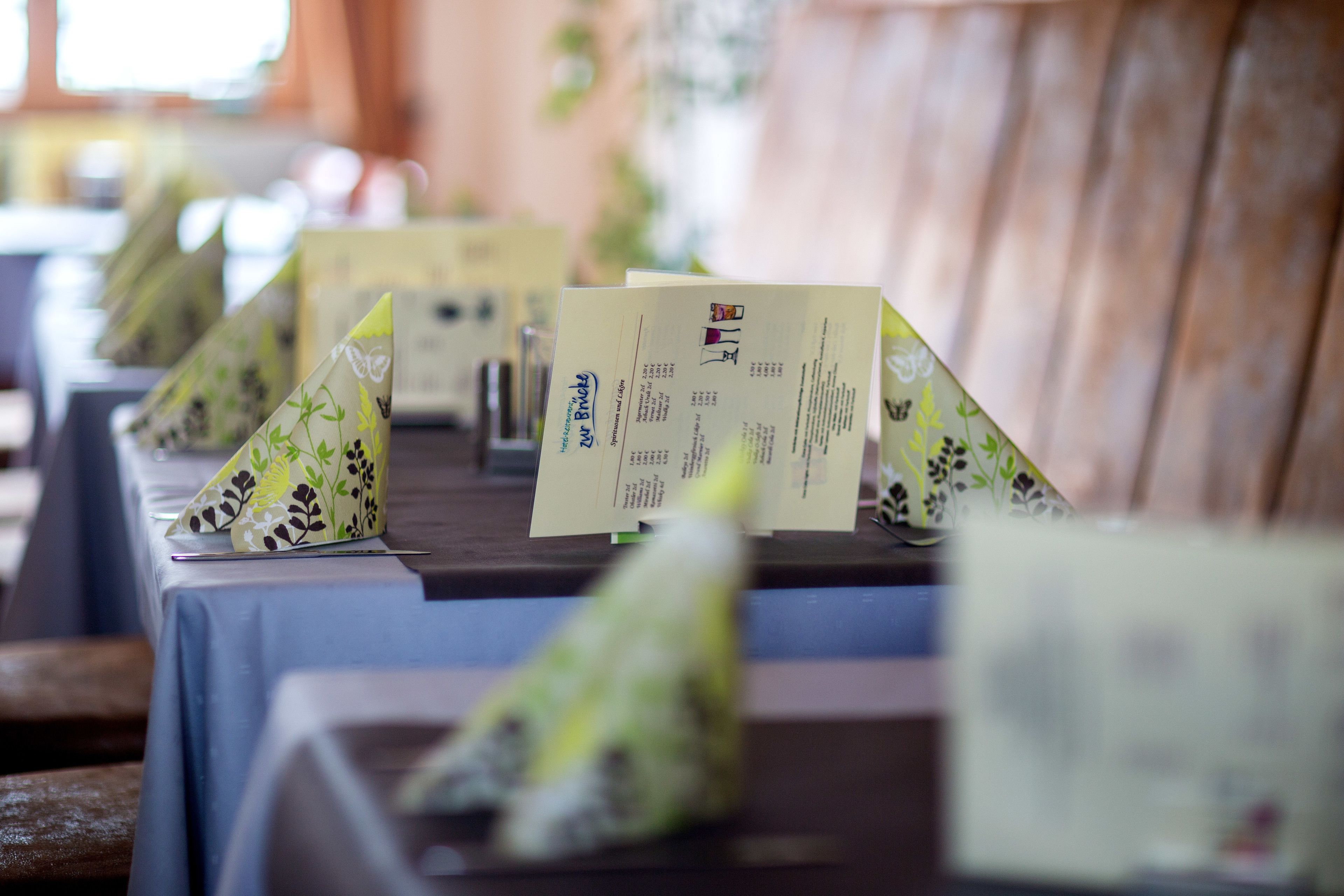 A row of tables with menus and a wooden backdrop.