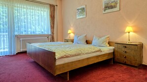 A bedroom with a wooden bed, two bedside tables with lamps, a radiator, and two framed pictures on the wall. - Hotel zur Brücke (Minheim)