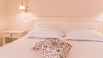 A neatly made bed with a white headboard, a bedside table, and a wall-mounted lamp.