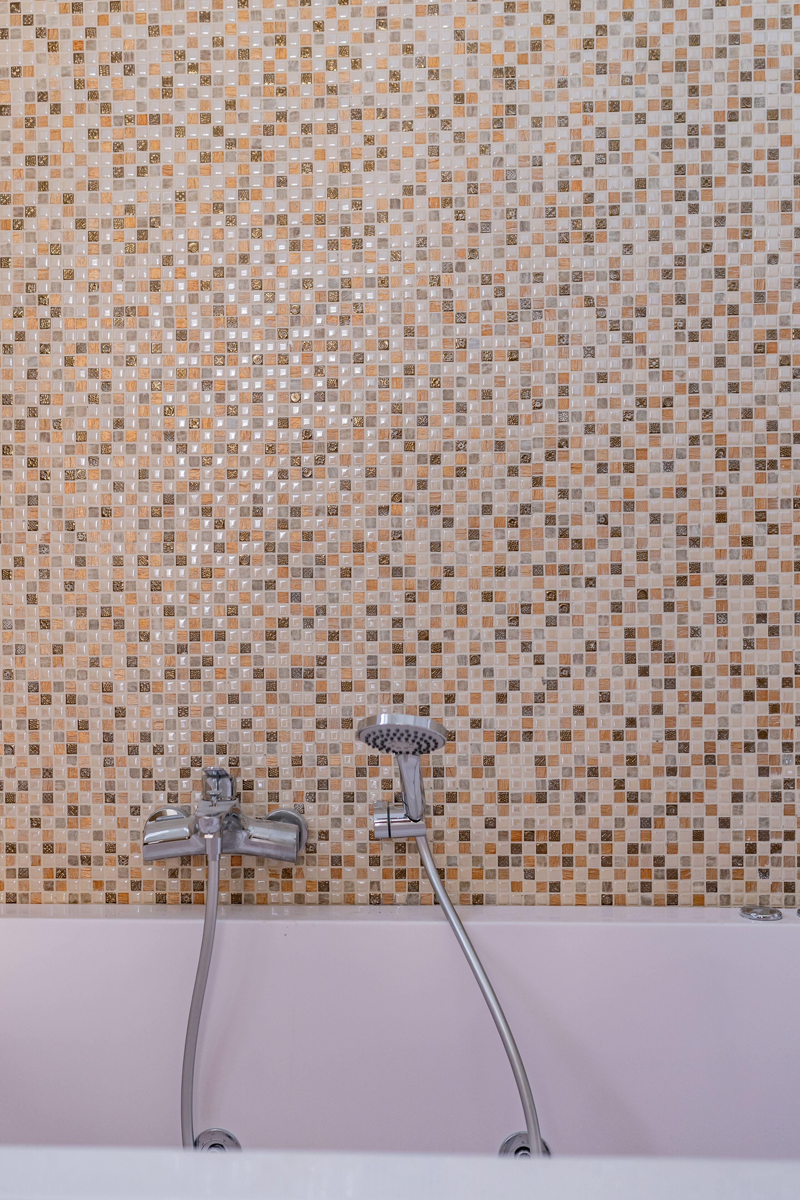 Une salle de bain avec un mur recouvert de mosaïques et une douche moderne.