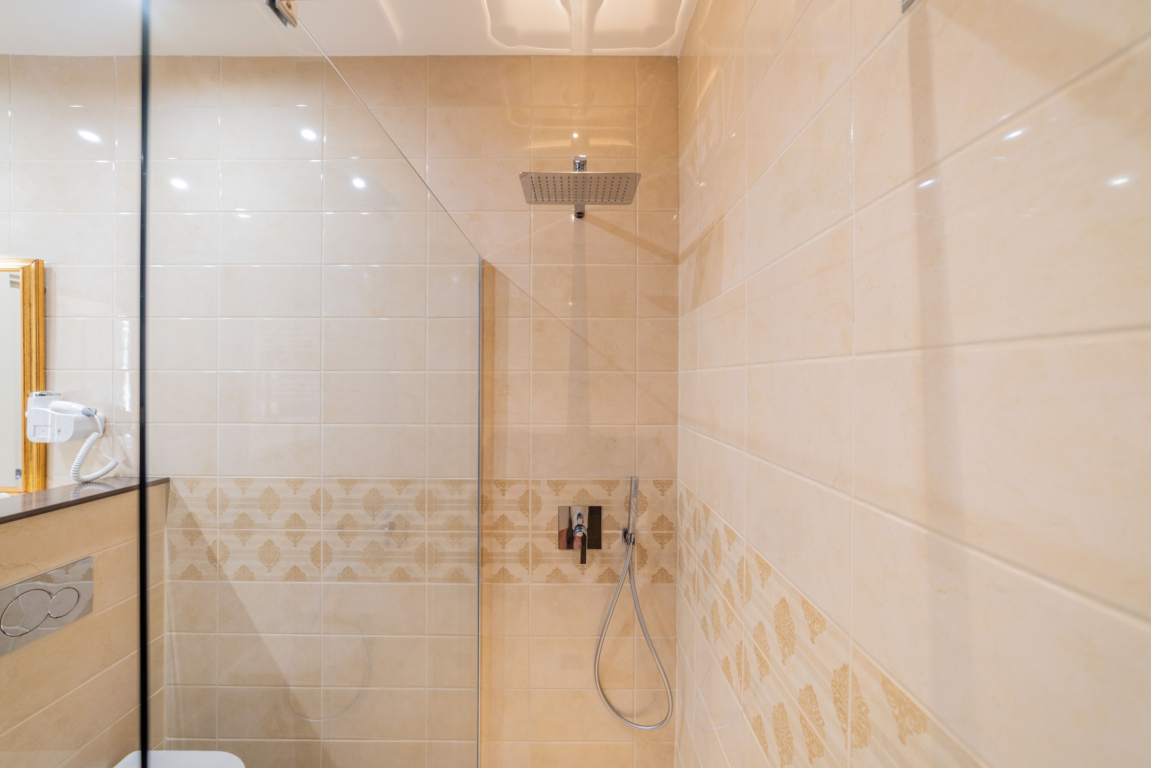 Una ducha con cabezal de ducha de mano y panel de control en la pared.