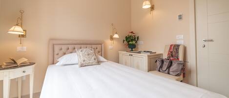 A hotel room with a large bed, bedside tables, a nightstand, a lamp, and a door.