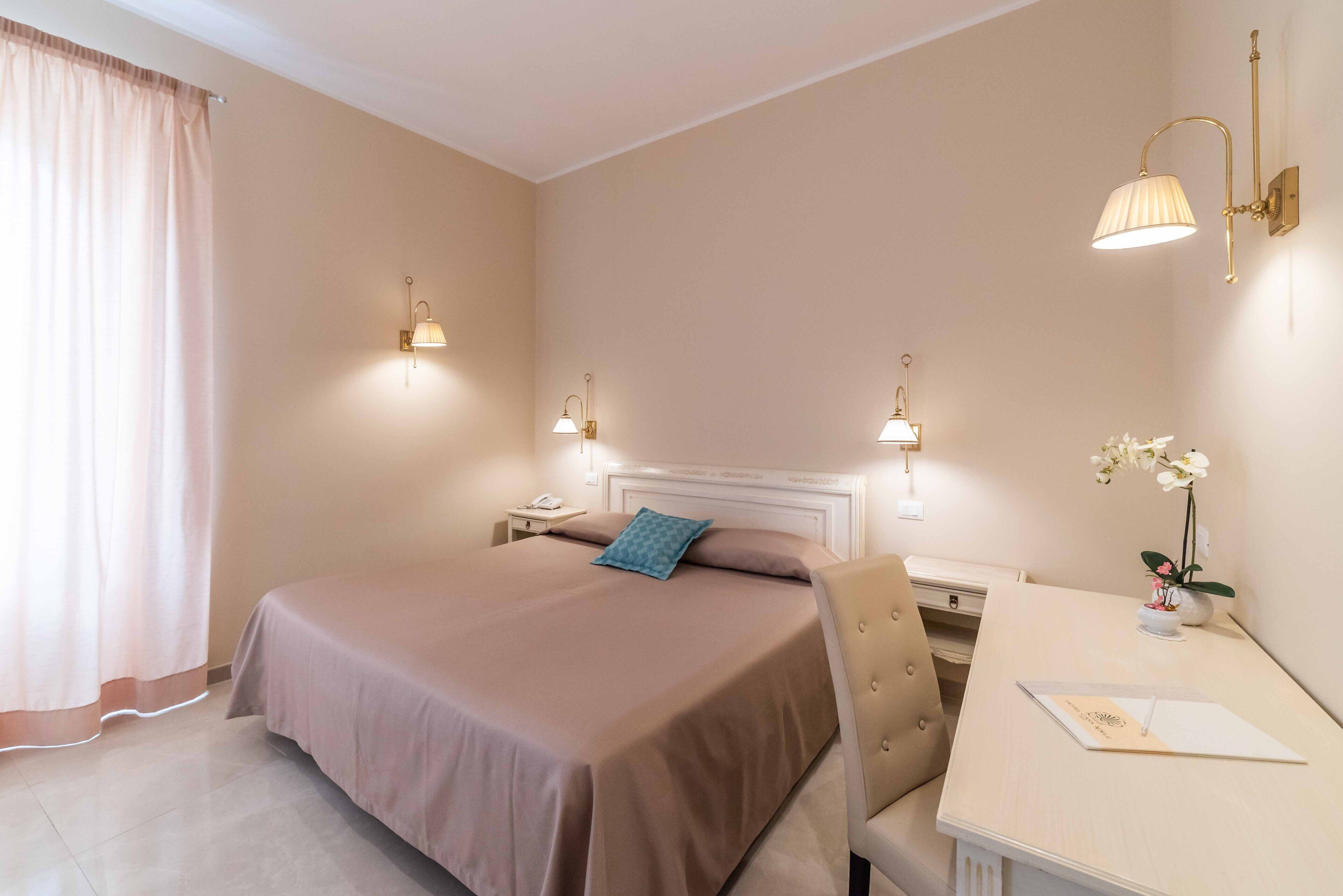 Une chambre d’hôtel comprenant un lit, des tables de chevet, un bureau et une chaise.