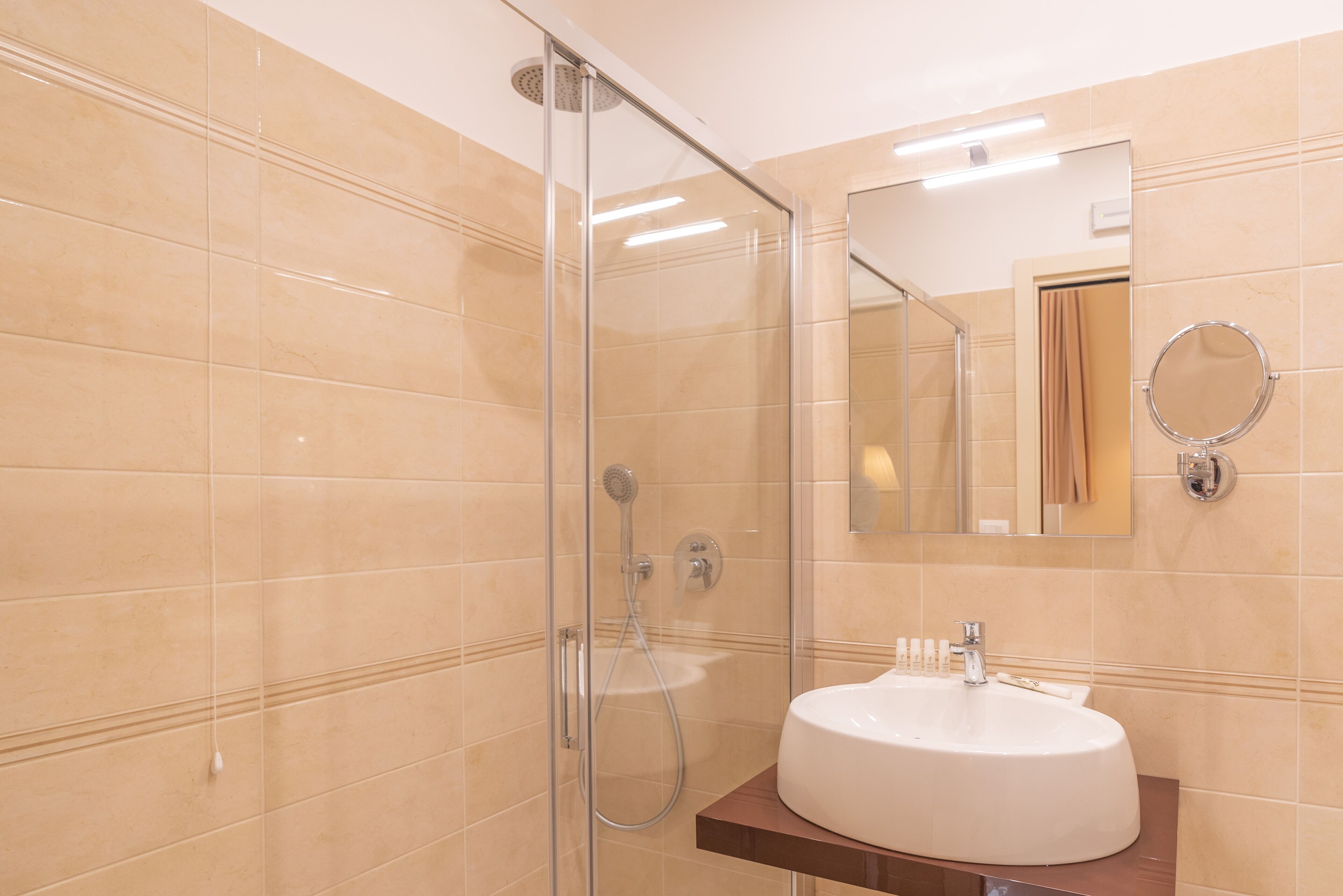 Une salle de bain avec une douche à parois de verre, un lavabo blanc et un miroir.