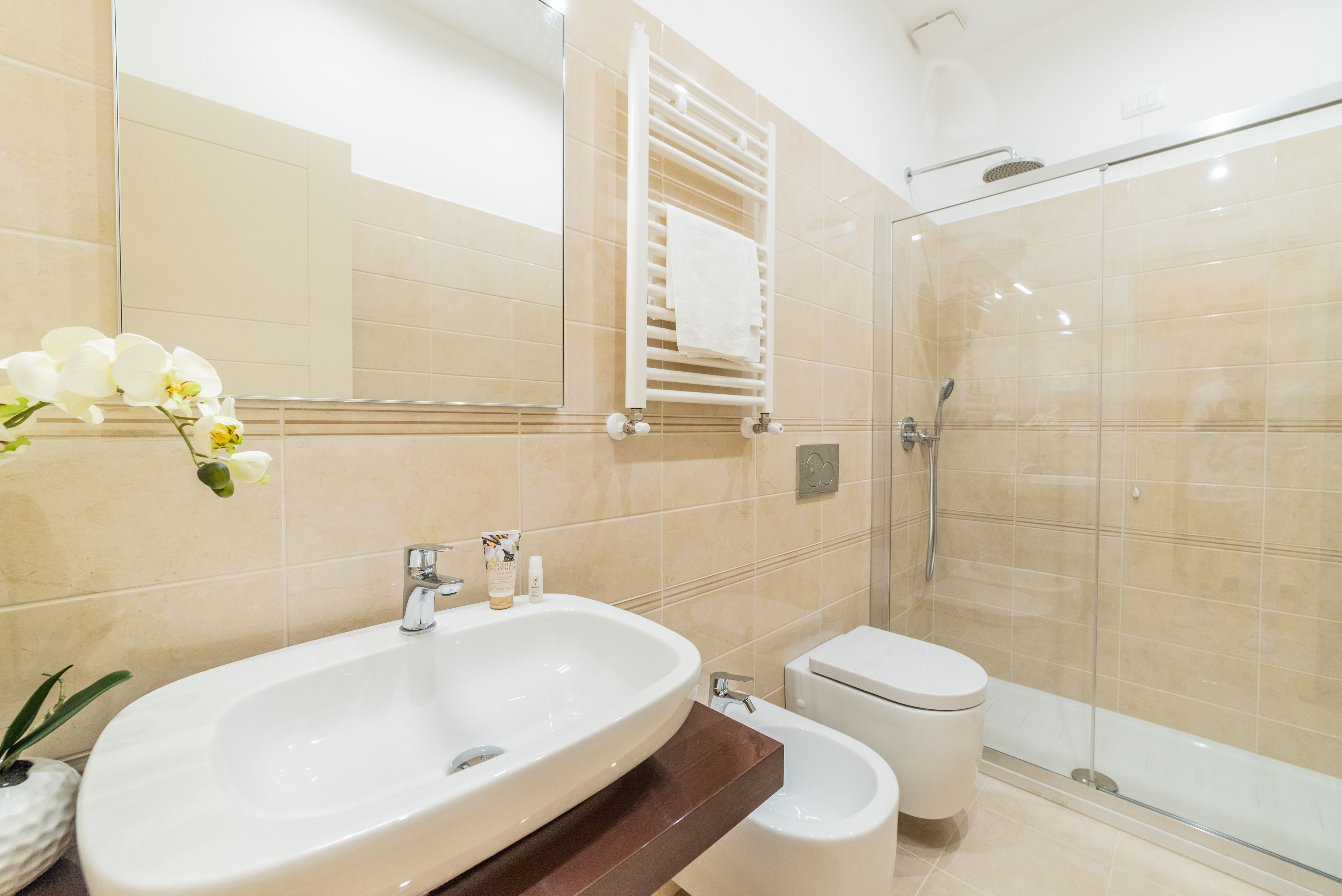 A modern bathroom with a large sink, a bidet, a toilet, and a glass-enclosed shower.