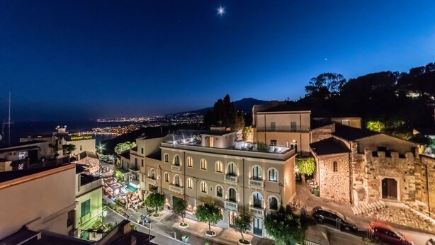 Vista nocturna de un pueblo histórico con un edificio destacado que presenta ventanas de arco y un patio central.