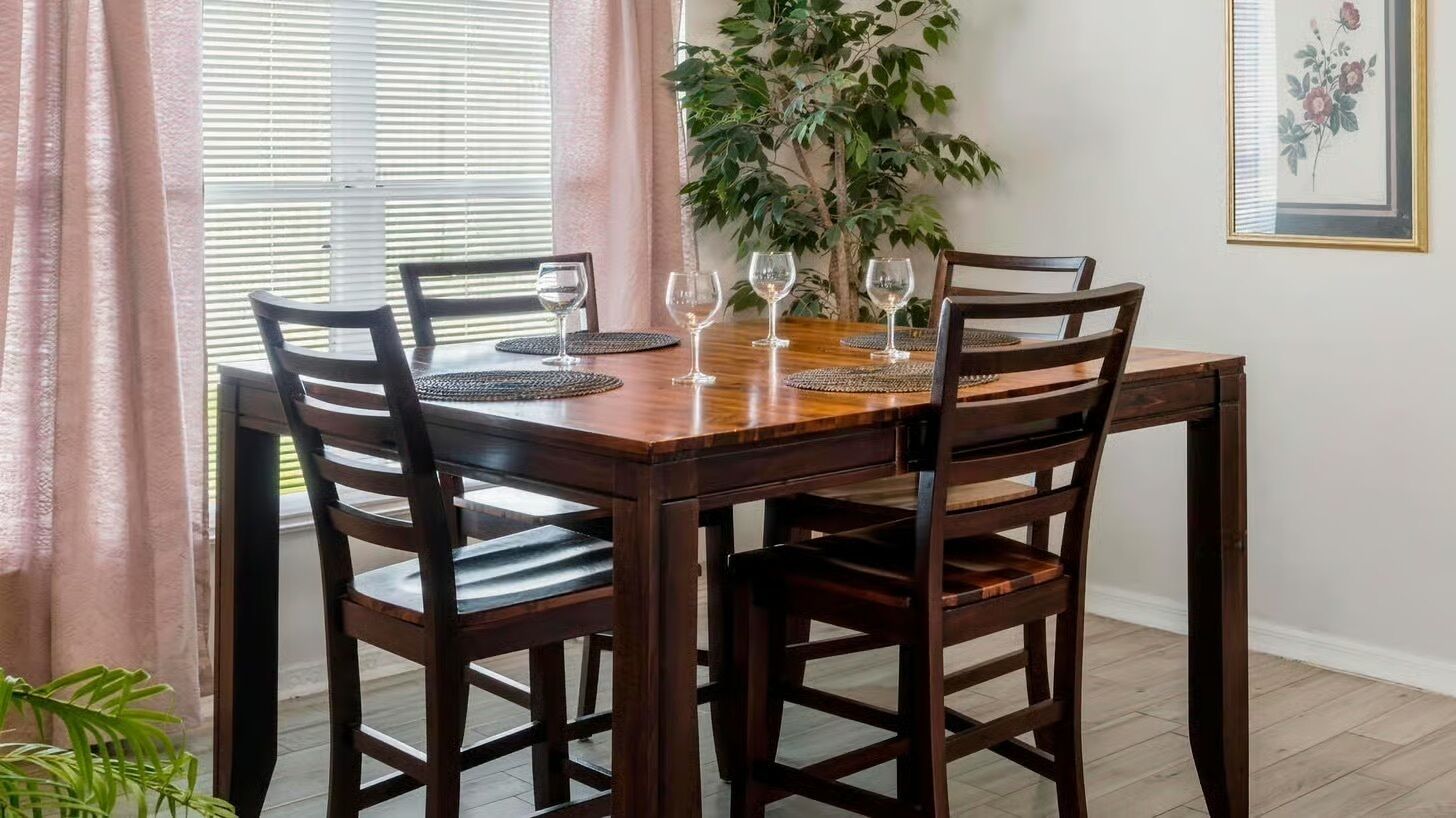 Una mesa de comedor con cuatro sillas, una planta en maceta y un cuadro en la pared.