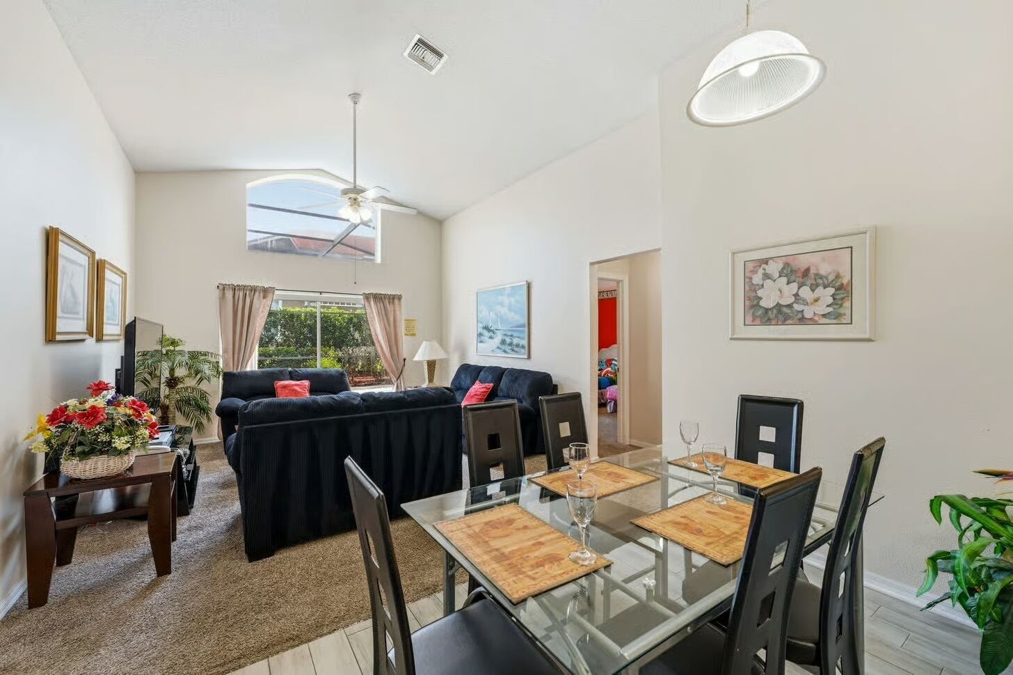 Un salon moderne avec un canapé, une table à manger, des chaises et un ventilateur de plafond.
