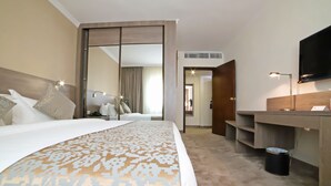 Une chambre d’hôtel avec un grand lit, un bureau, une télévision et un miroir.