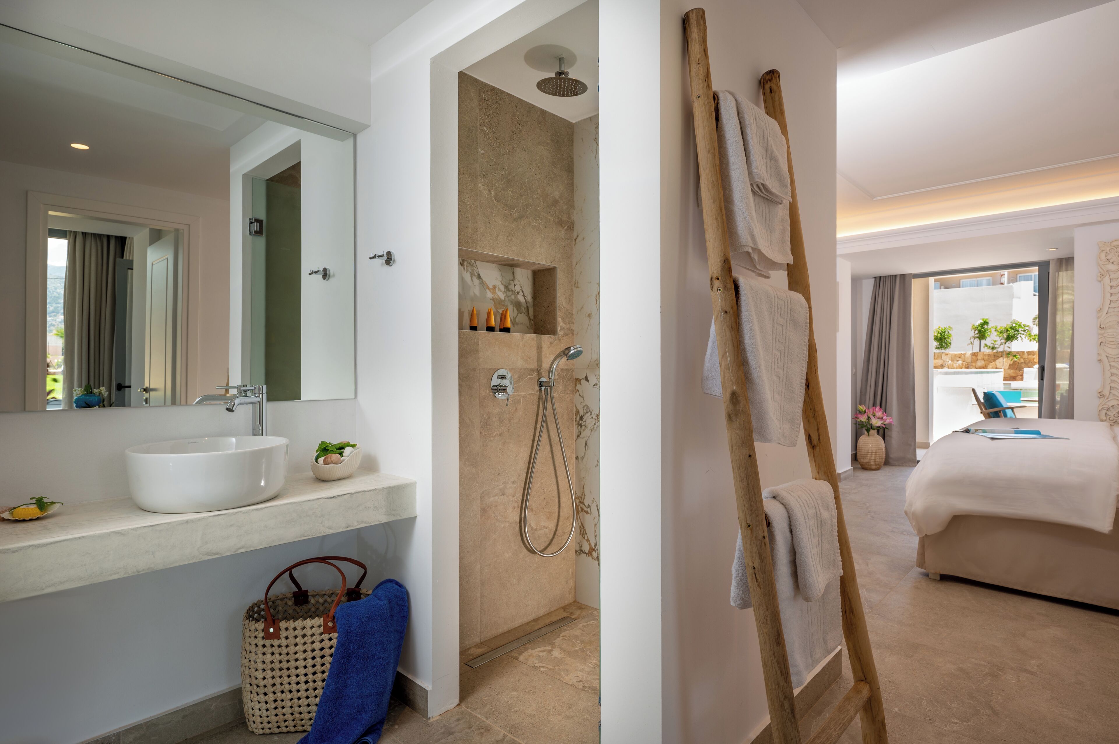 Un baño moderno con lavamanos, espejo, ducha y una escalera de madera apoyada en la pared.