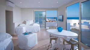 Une chambre d’hôtel moderne dotée d’un balcon, d’un coin repas et d’une grande fenêtre donnant sur la mer.
