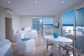 Une chambre d’hôtel moderne dotée d’un balcon, d’un coin repas et d’une grande fenêtre donnant sur la mer.