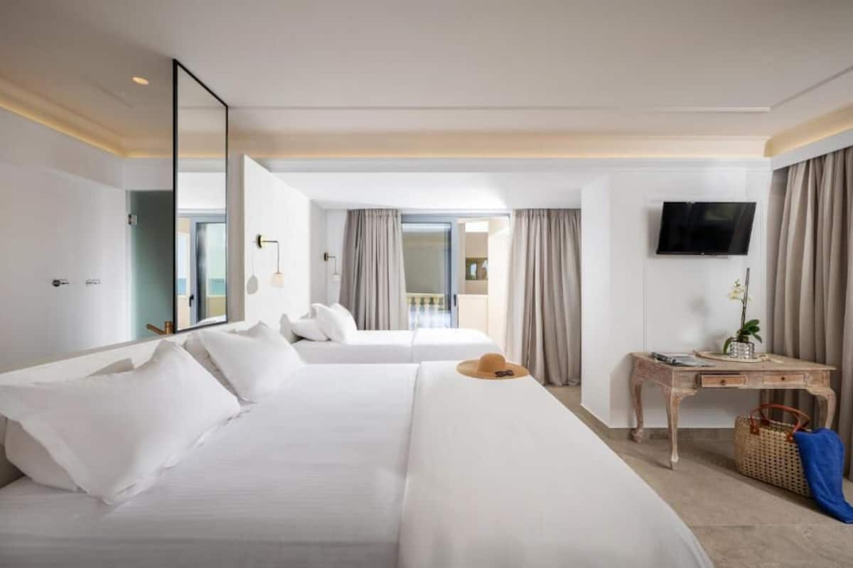 Habitación de hotel con dos camas, un escritorio, un televisor y vistas al exterior.