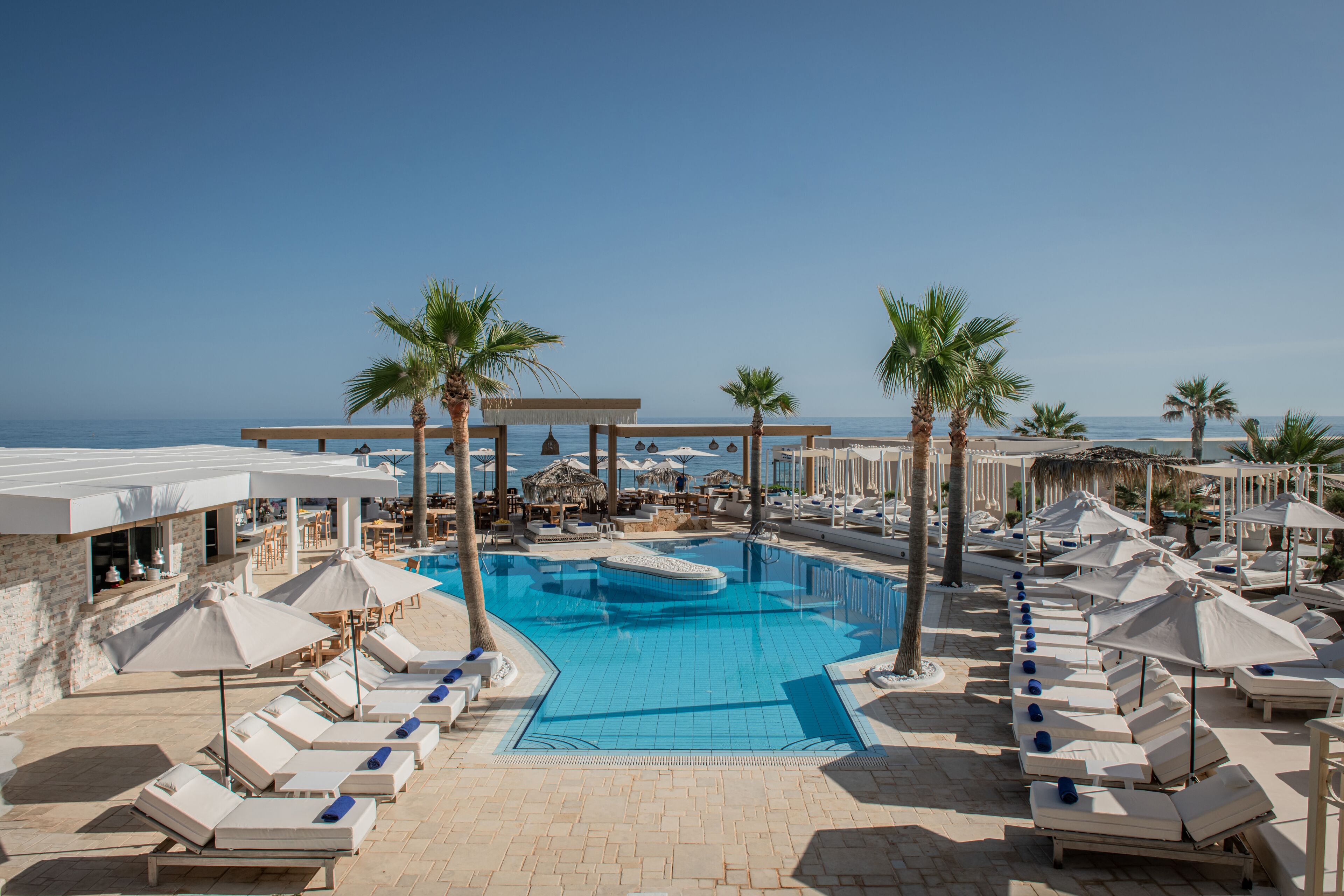 Un espace piscine avec des chaises longues et des parasols, un jacuzzi et une vue sur la mer.