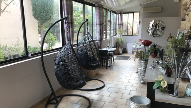 A modern interior with large windows, a dining area, and a variety of potted plants. - Hotel Le Lys d'Or (Vauvert)