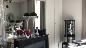 A modern kitchen with a fireplace, a large mirror, and a dining area with a patterned floor. - Hotel Le Lys d'Or (Vauvert)