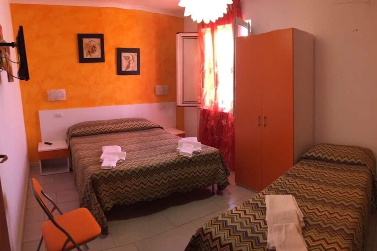 Una habitación con dos camas individuales, un armario, un escritorio y una silla.