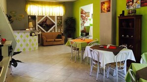 A dining area with a green wall, a brown sofa, and a white table with chairs. - B&B Lolly (Mileto)