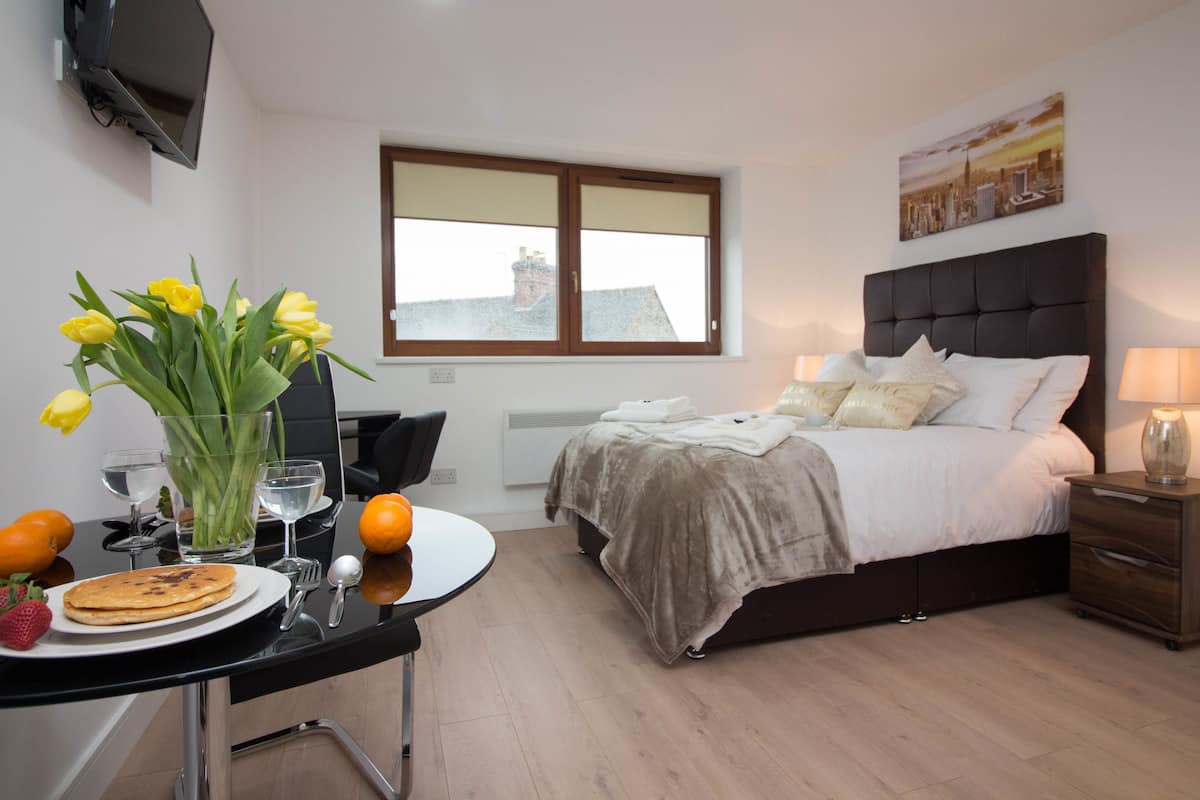 Un dormitorio moderno con cama, mesita de noche y ventana con persianas.