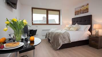 A modern bedroom with a bed, bedside table, and a window with blinds.