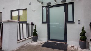 A modern building entrance with a glass door, a metal gate, and two potted plants. - Trafalgar House (Stoke-on-Trent)