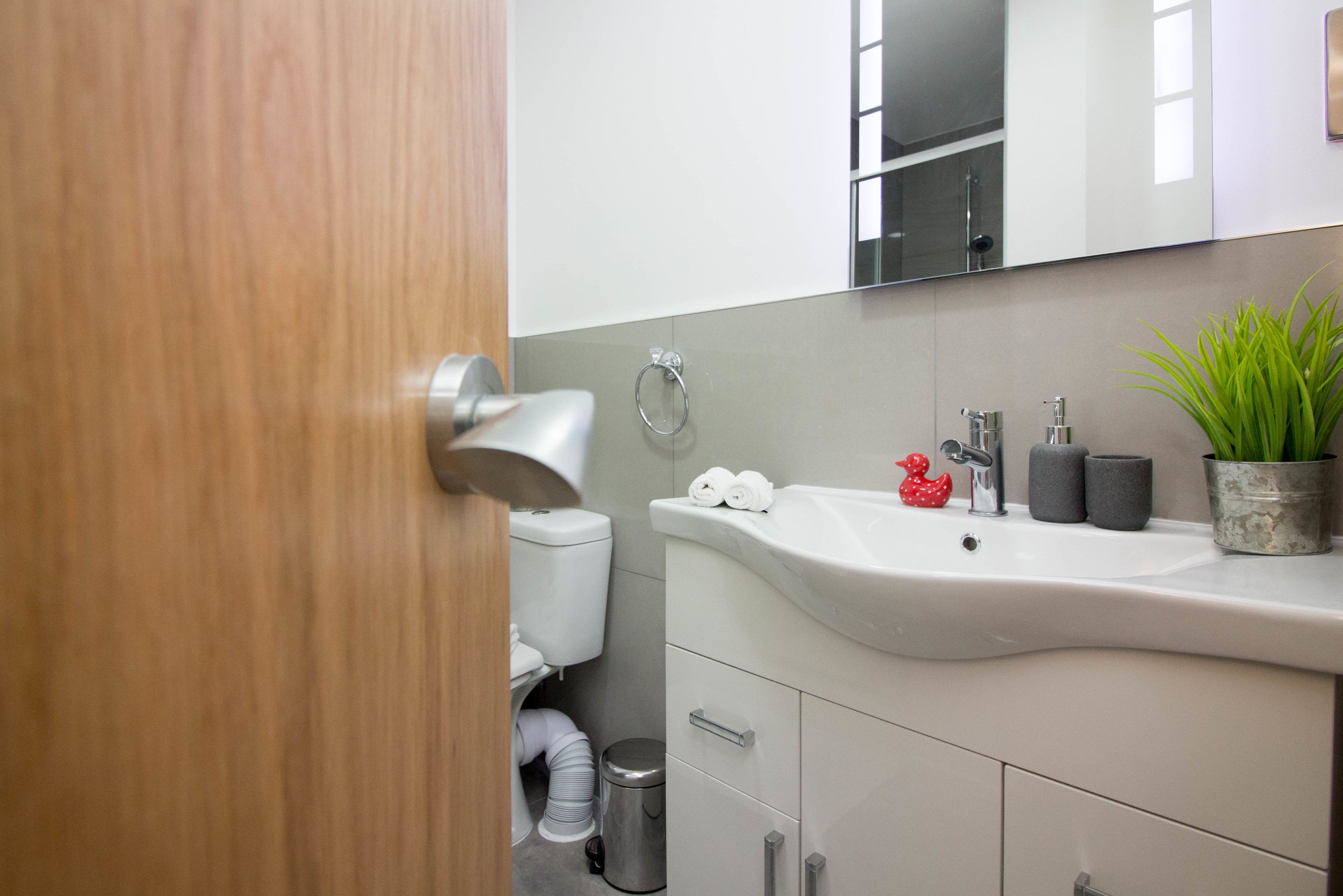 Un baño moderno con un lavabo blanco, un espejo y un inodoro.