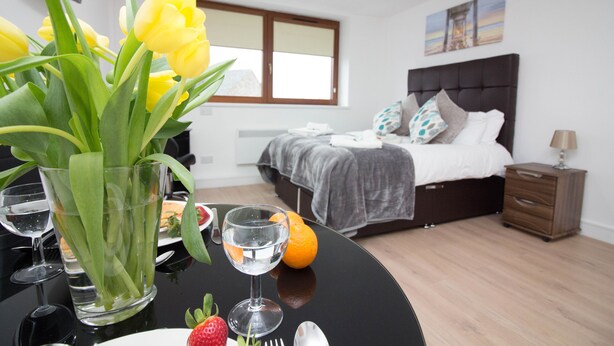 A modern bedroom with a large bed, a bedside table, and a nightstand. - Trafalgar House (Stoke-on-Trent)