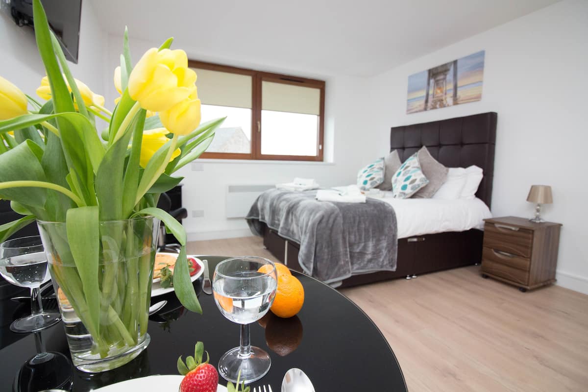 Un dormitorio moderno con una cama grande, una mesita de noche y un mueble auxiliar.