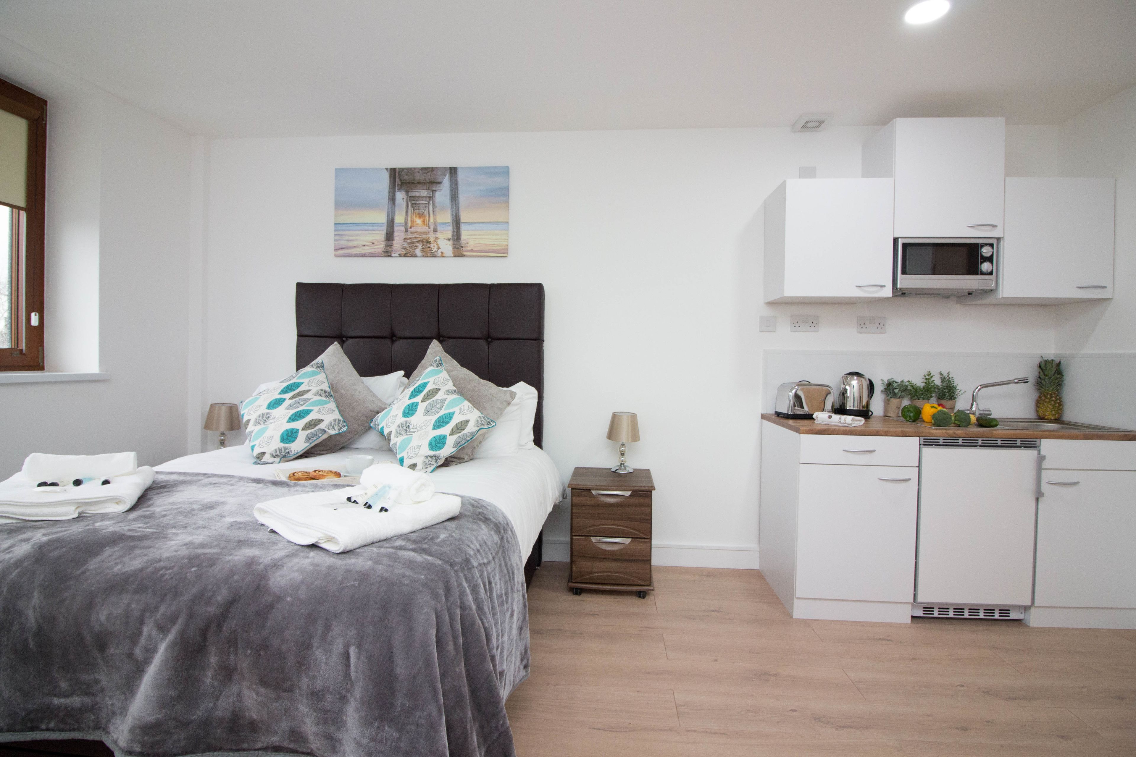 A bedroom with a bed, bedside table, and a view of the beach through a window.
