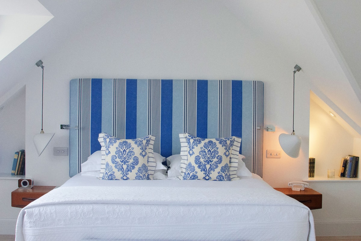 A bedroom with a large bed, striped headboard, and bedside lamps.