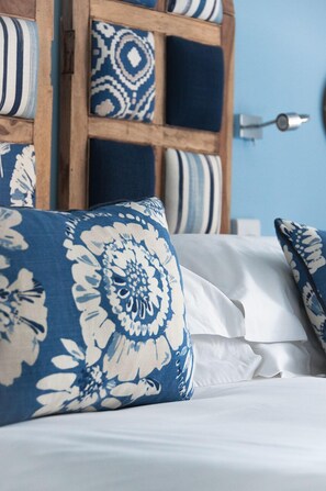 A bed with white linens and blue floral pillows. - Trevose Harbour House (St Ives)