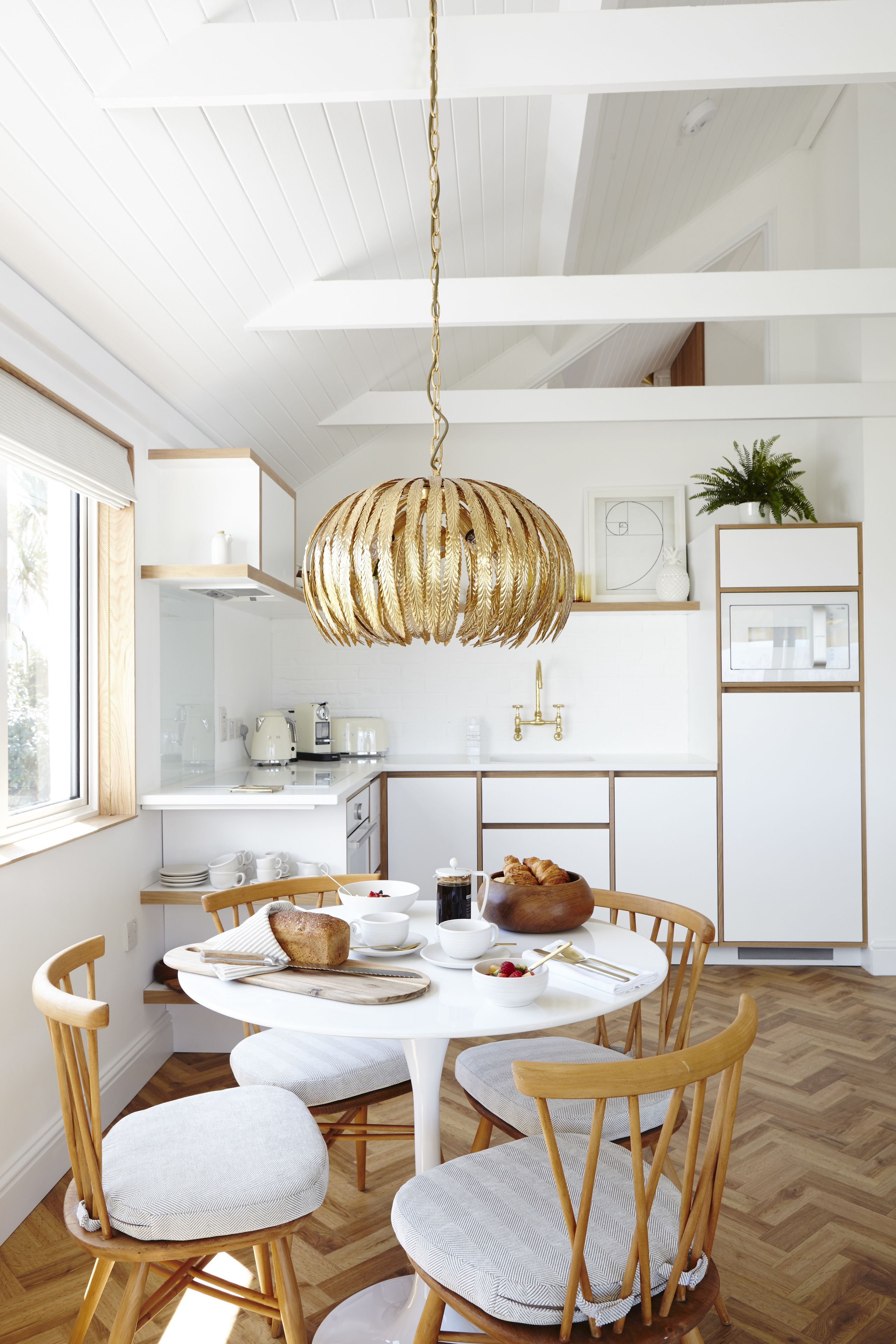 A modern kitchen with white cabinetry, a round dining table, and wooden chairs.