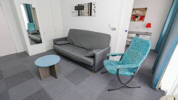 En moderne stue med en grå sofa, en blå stol med mønster og et lille rundt bord.