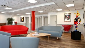 Un hall d’entrée moderne avec des espaces de détente, un pilier rouge et des œuvres d’art accrochées aux murs.