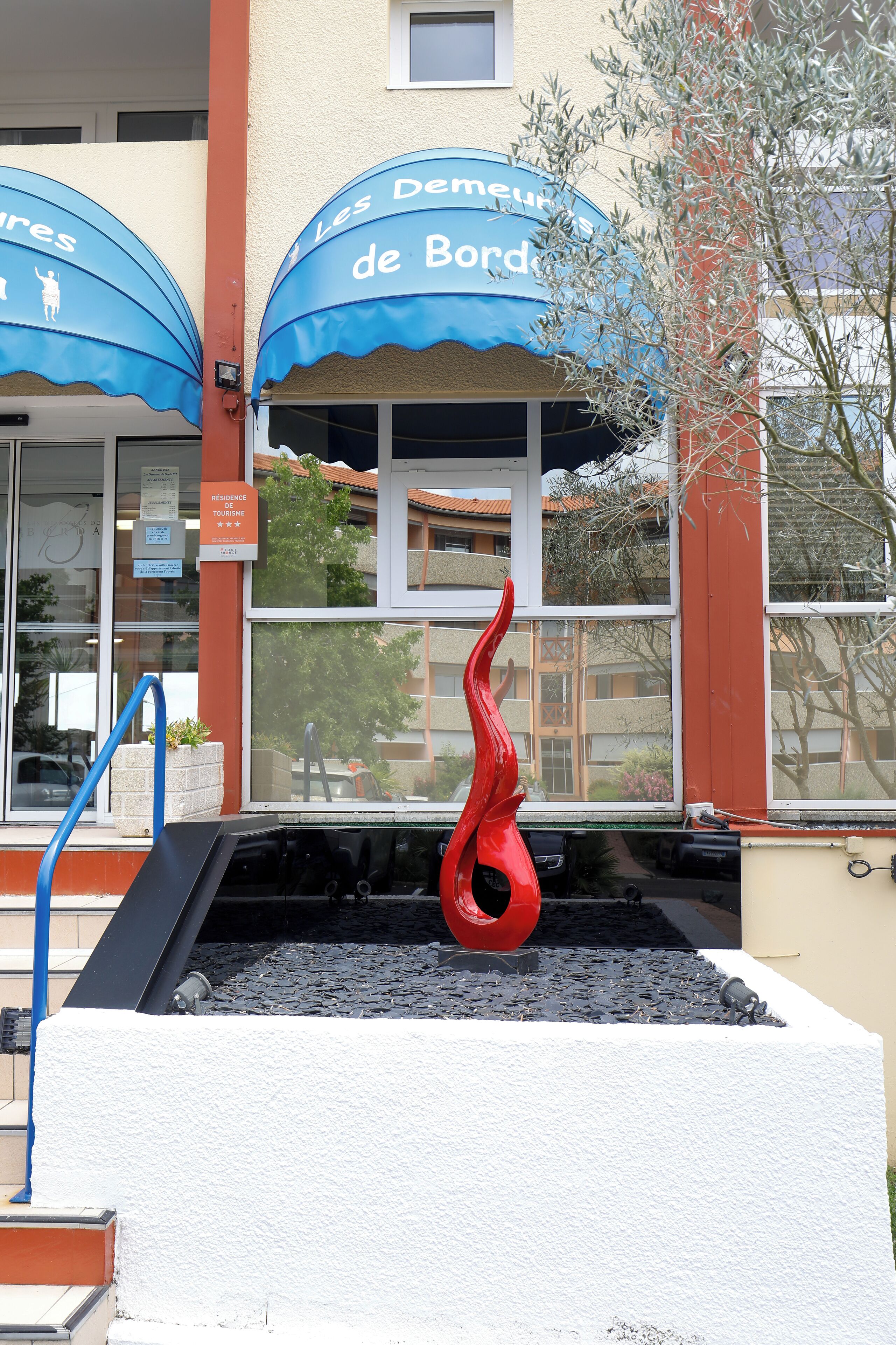 Ein Gebäude mit einer blauen Markise, auf der "Les Demeures de Bord" steht.