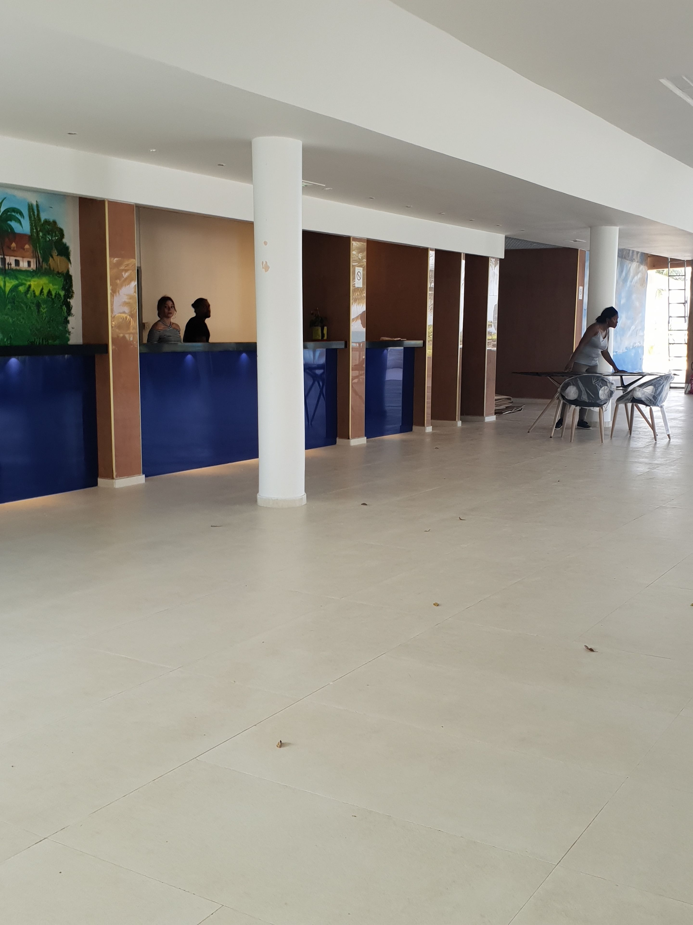 A spacious lobby with a reception desk, a large column, and a view of the outdoors.