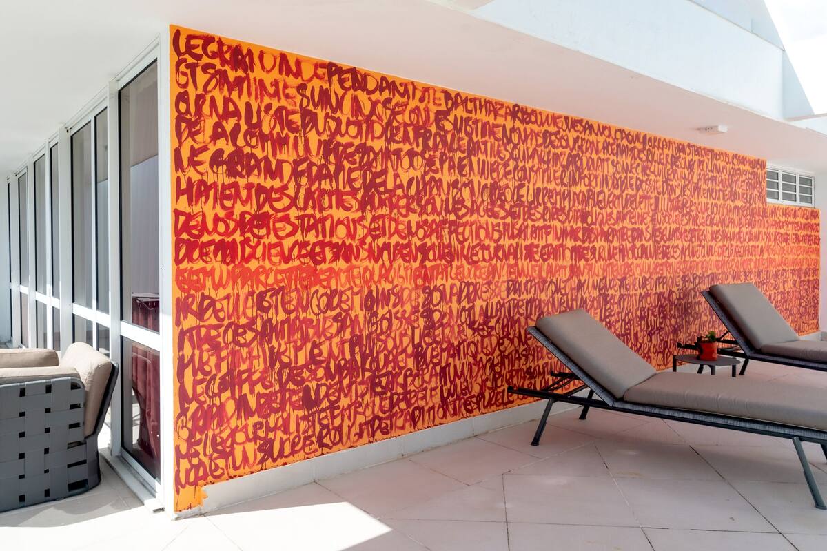 A modern indoor space with a large window, a wall with graffiti art, and two lounge chairs.