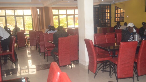 A restaurant with red chairs and tables, large windows, and a tiled floor.