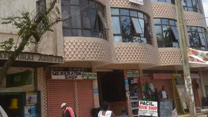 A multi-story building with a checkered facade, a visible office sign, and a bookshop sign.