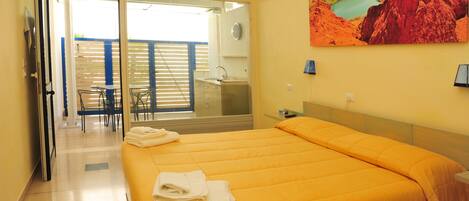 A hotel room with a bed, a bathroom, and a balcony with a view of a lake.