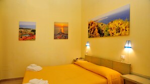 A hotel room with a bed, two wall-mounted lamps, and three paintings. - Camere sul Lungomare (Otranto)
