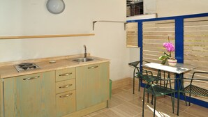 A compact kitchen with a sink, cabinets, and a small dining area with a table and chairs. - Camere sul Lungomare (Otranto)