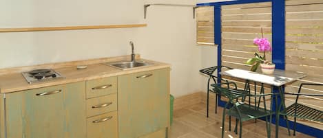 Una cocina compacta con lavamanos, armarios y un pequeño comedor con mesa y sillas.