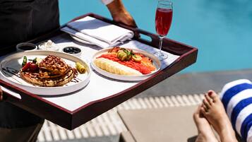 A tray with food and a drink, a poolside setting, and a person reclining.