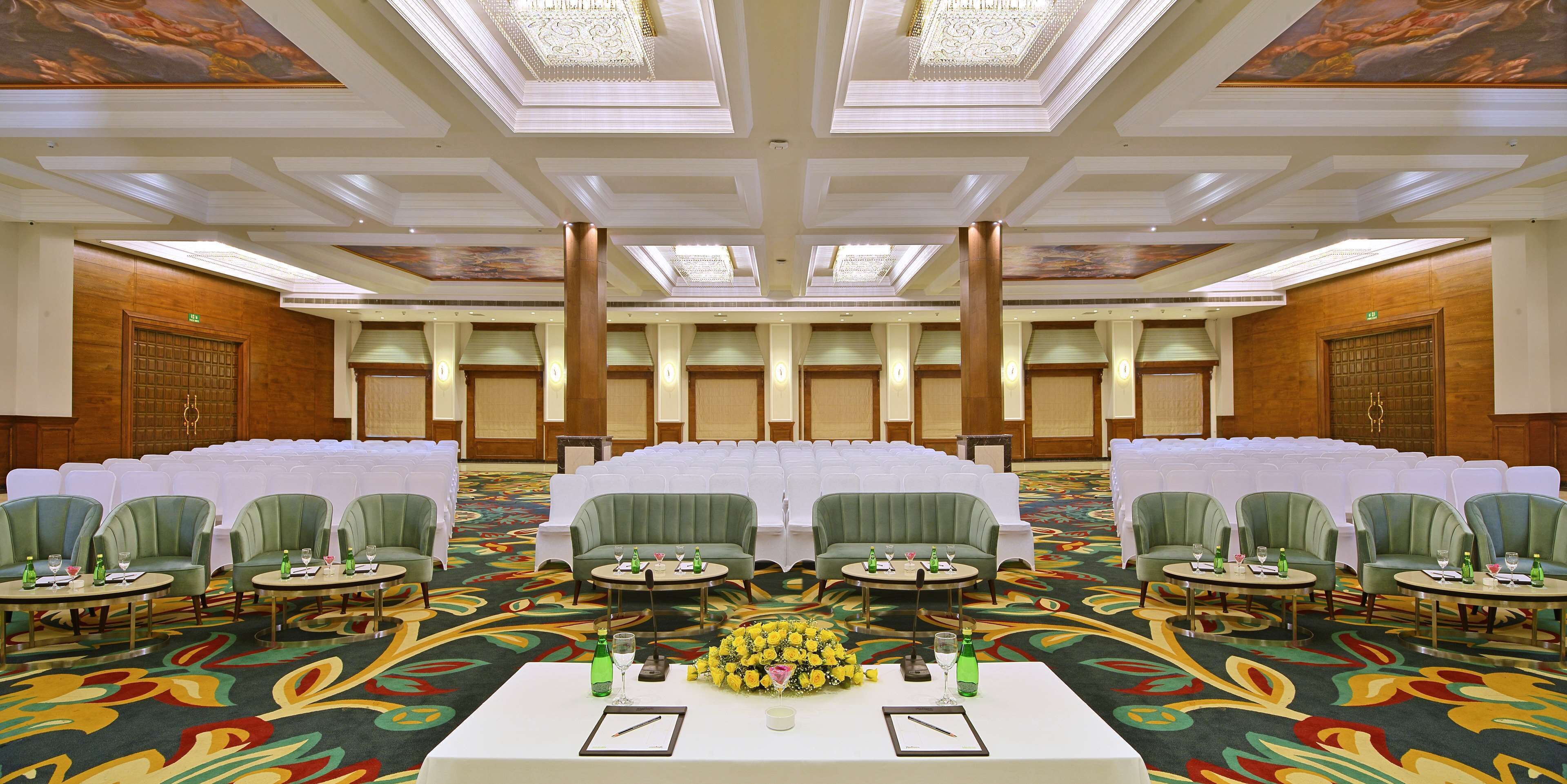 A conference room with round tables, green chairs, and a floral centerpiece.