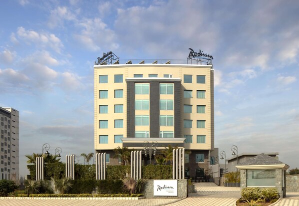 Um hotel Radisson com design moderno, apresentando uma entrada central, vários andares e um terraço com uma placa.