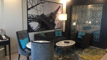 Una sala de estar moderna con una gran obra de arte de la Torre Eiffel, una mesa de centro redonda y una alfombra estampada.