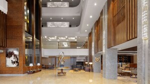A spacious lobby with a high ceiling, modern lighting fixtures, and a central seating area. - Radisson Chandigarh Zirakpur (Dera Bassi)